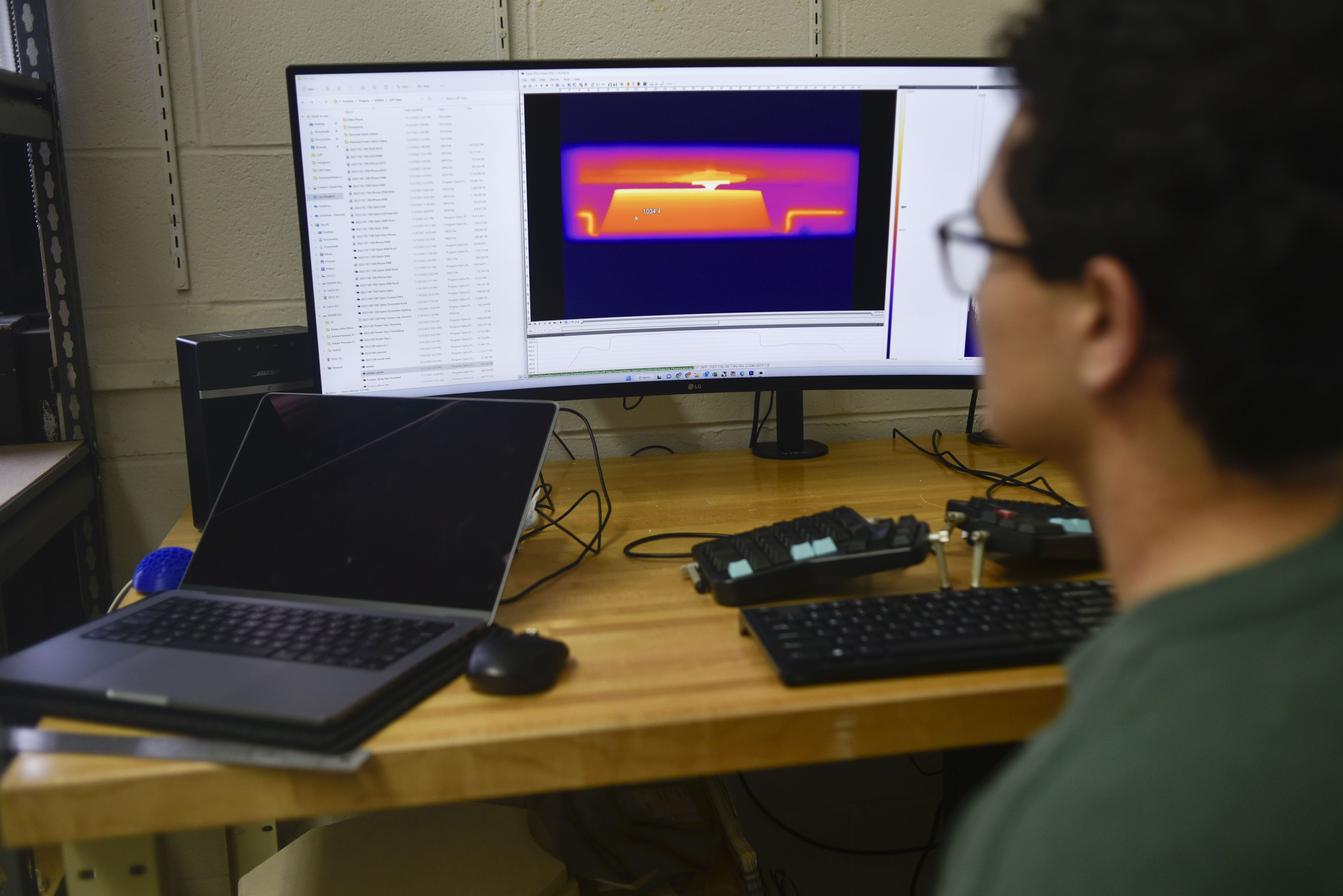 Ethan Townsend looks a computer displaying thermal information about the molten glass 3D printer.