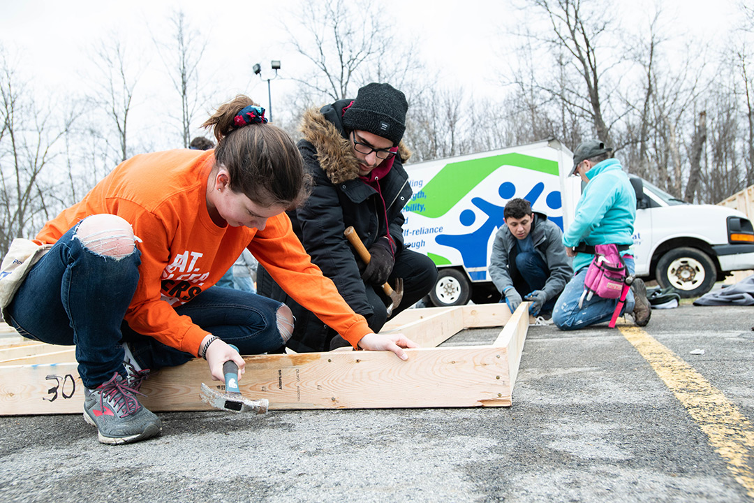 Participants nail wall frame studs together.