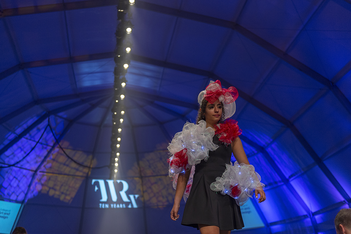 A wearable sculpture that lights up is modeled on the runway.