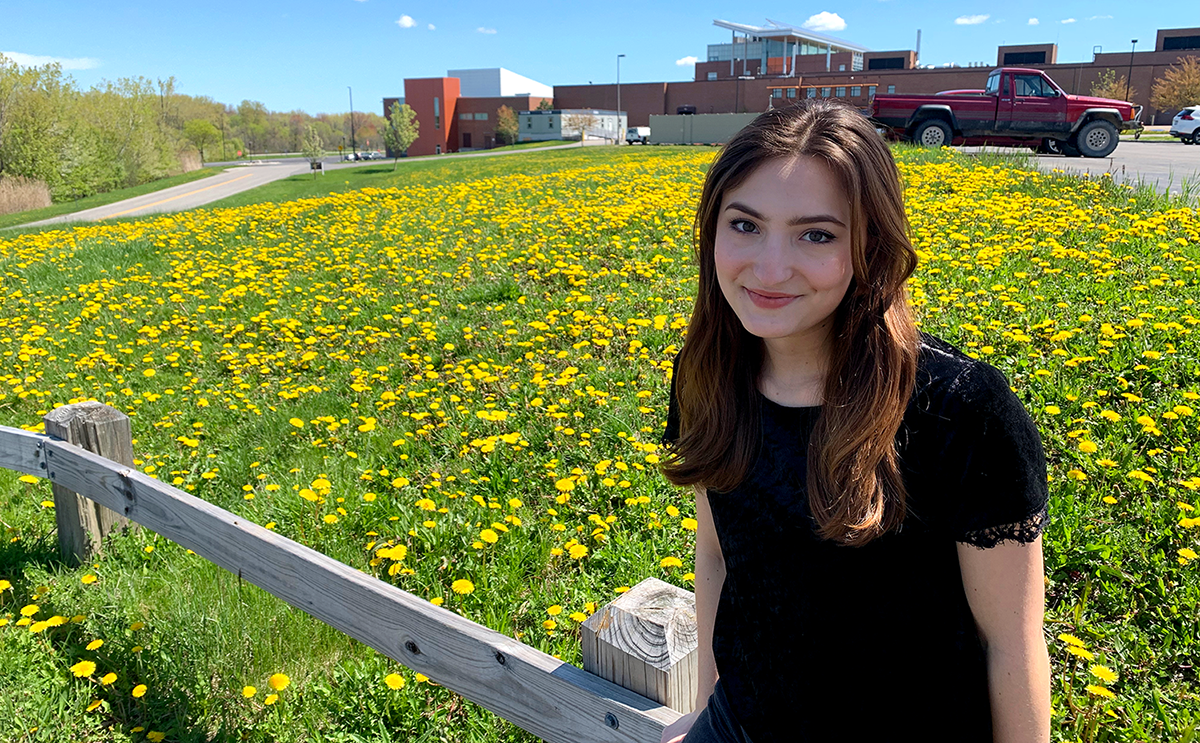 A portrait of Gia Caruso in front of a bed of flowers.
