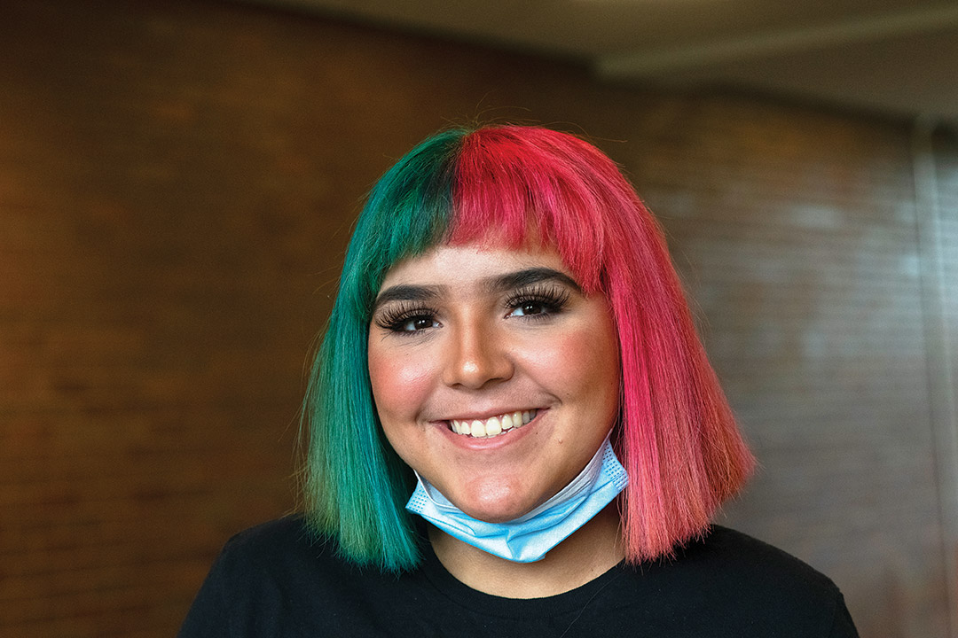 student with short, straight hair half dyed teal, half dyed red.