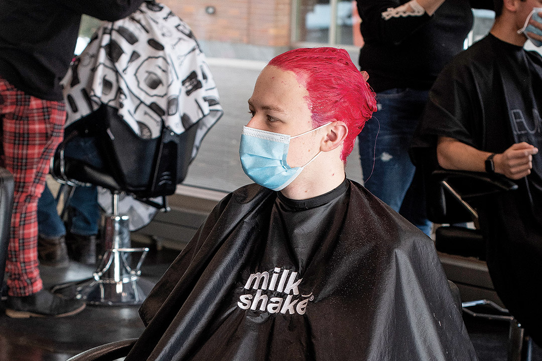 student in a salon chair with bright red hair.