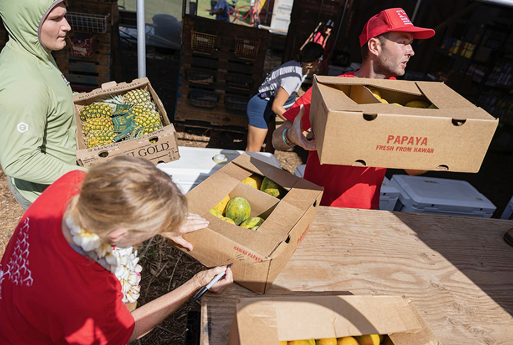 People hold boxed of food and supplies as part of wildfire relief efforts on Maui.