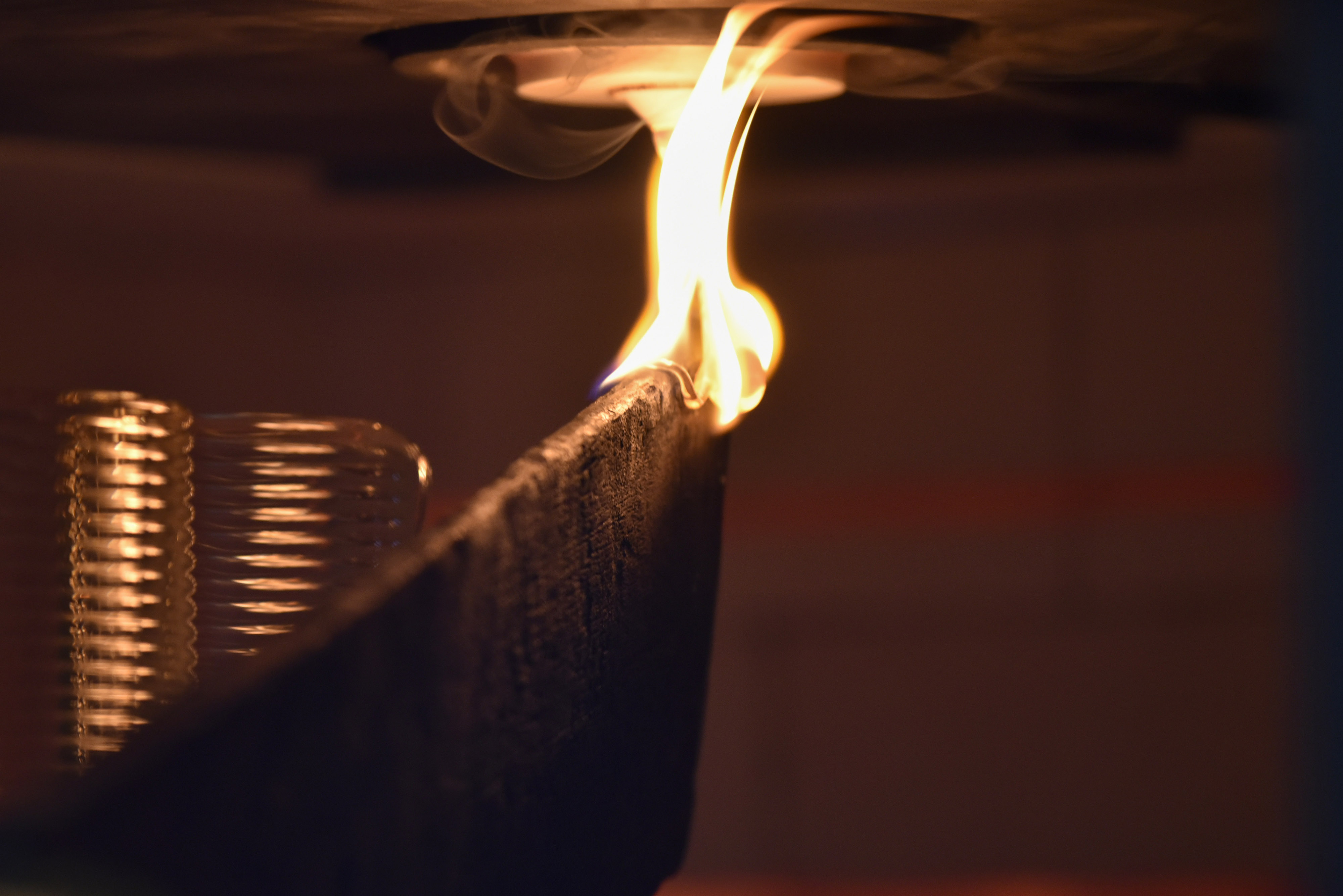 A detailed look inside a molten glass 3D printer, featuring flames and glass coils.