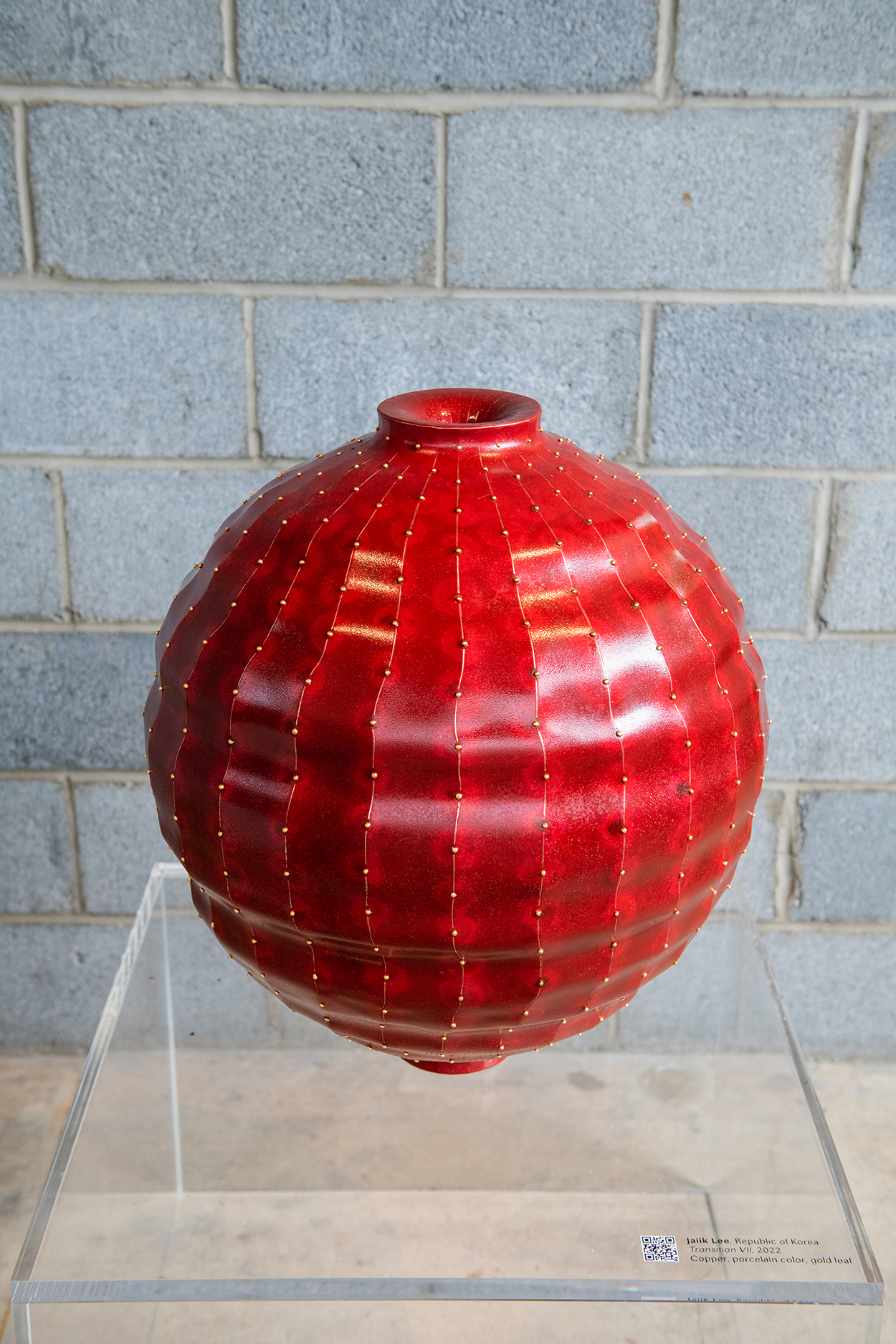 A portrait view of a red, copper, round vessel