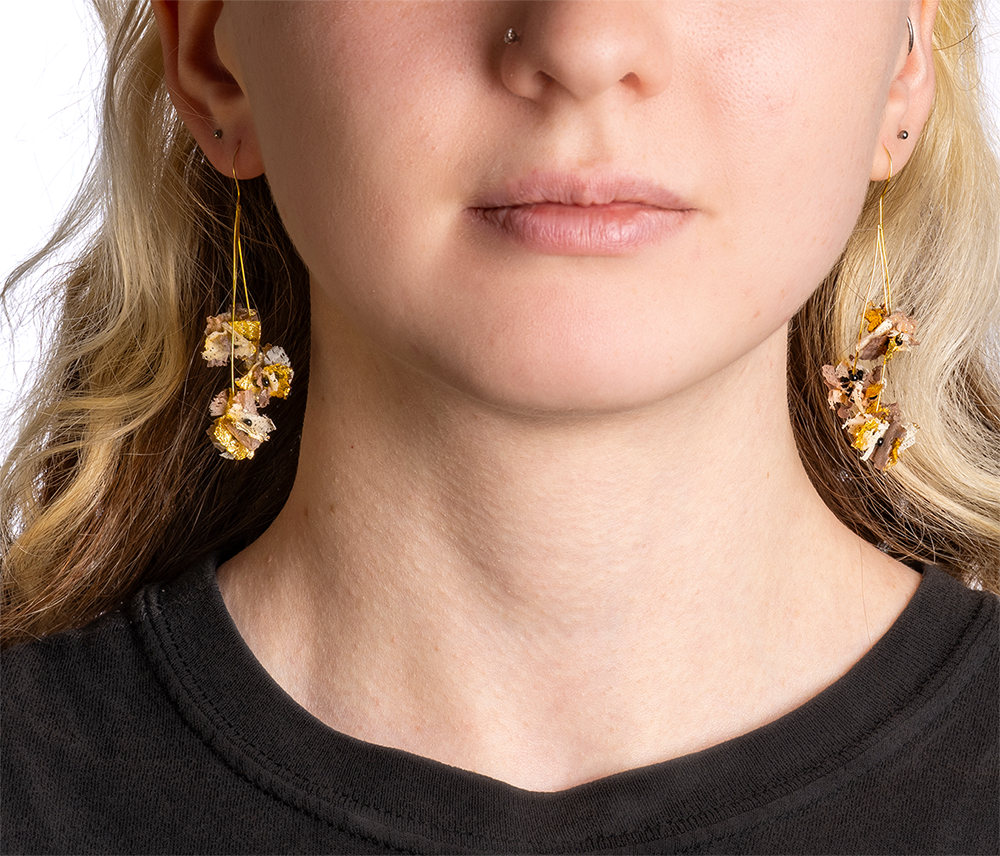Wood-shaving earring on a person's ears.