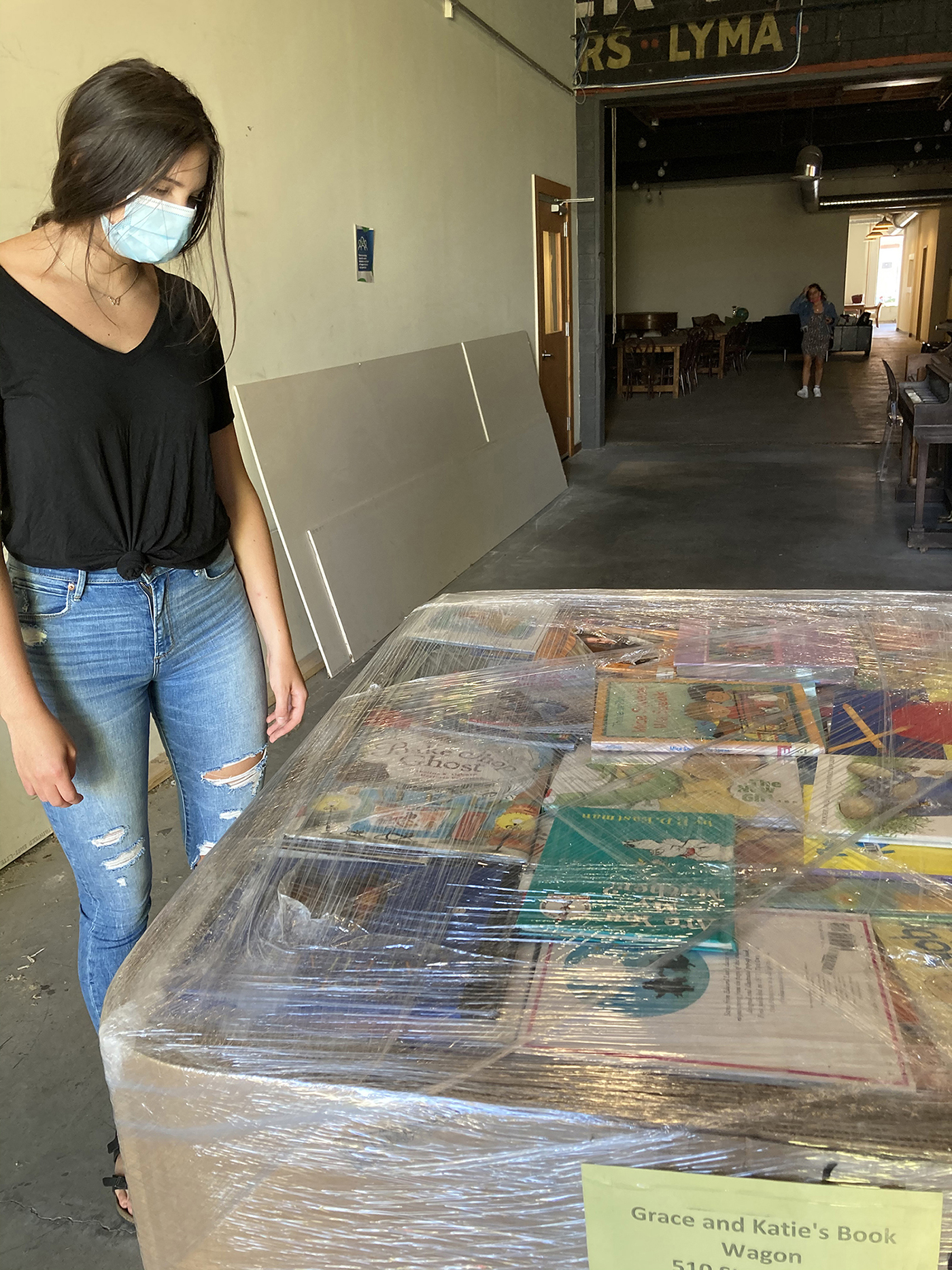 Katie Hobler stands next to a crate of books to be donated.