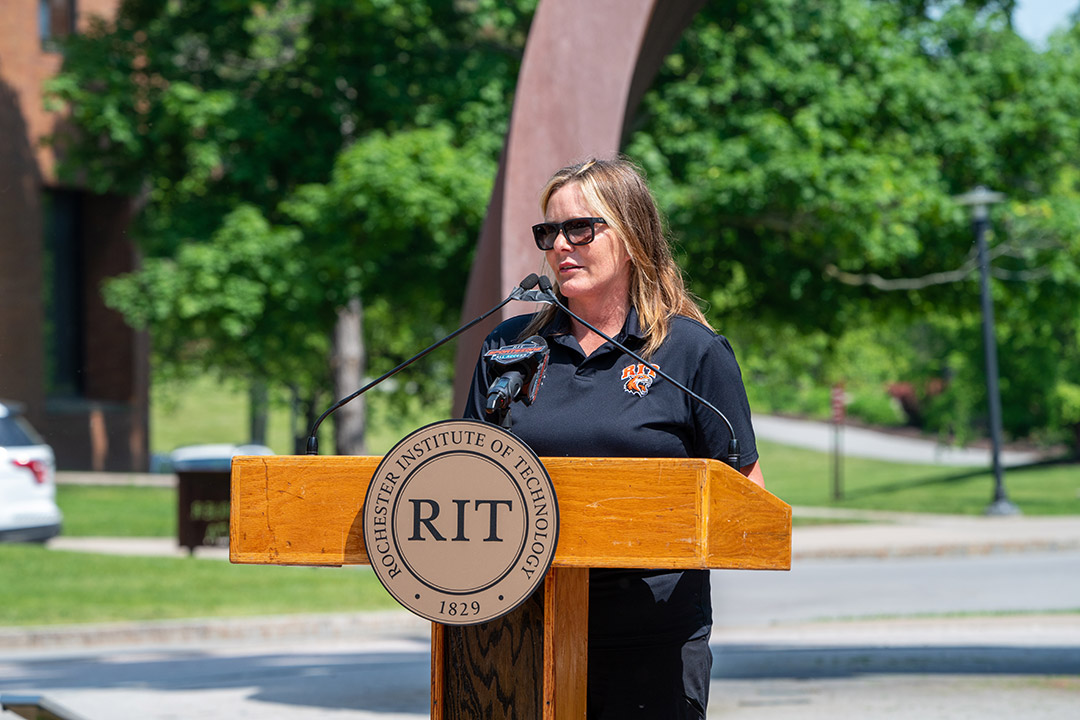 woman speaking at podium outdoors.