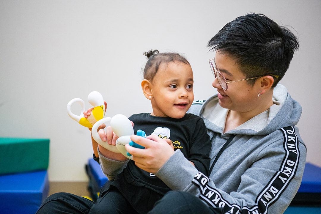 adult holding child holding therapeutic toys.