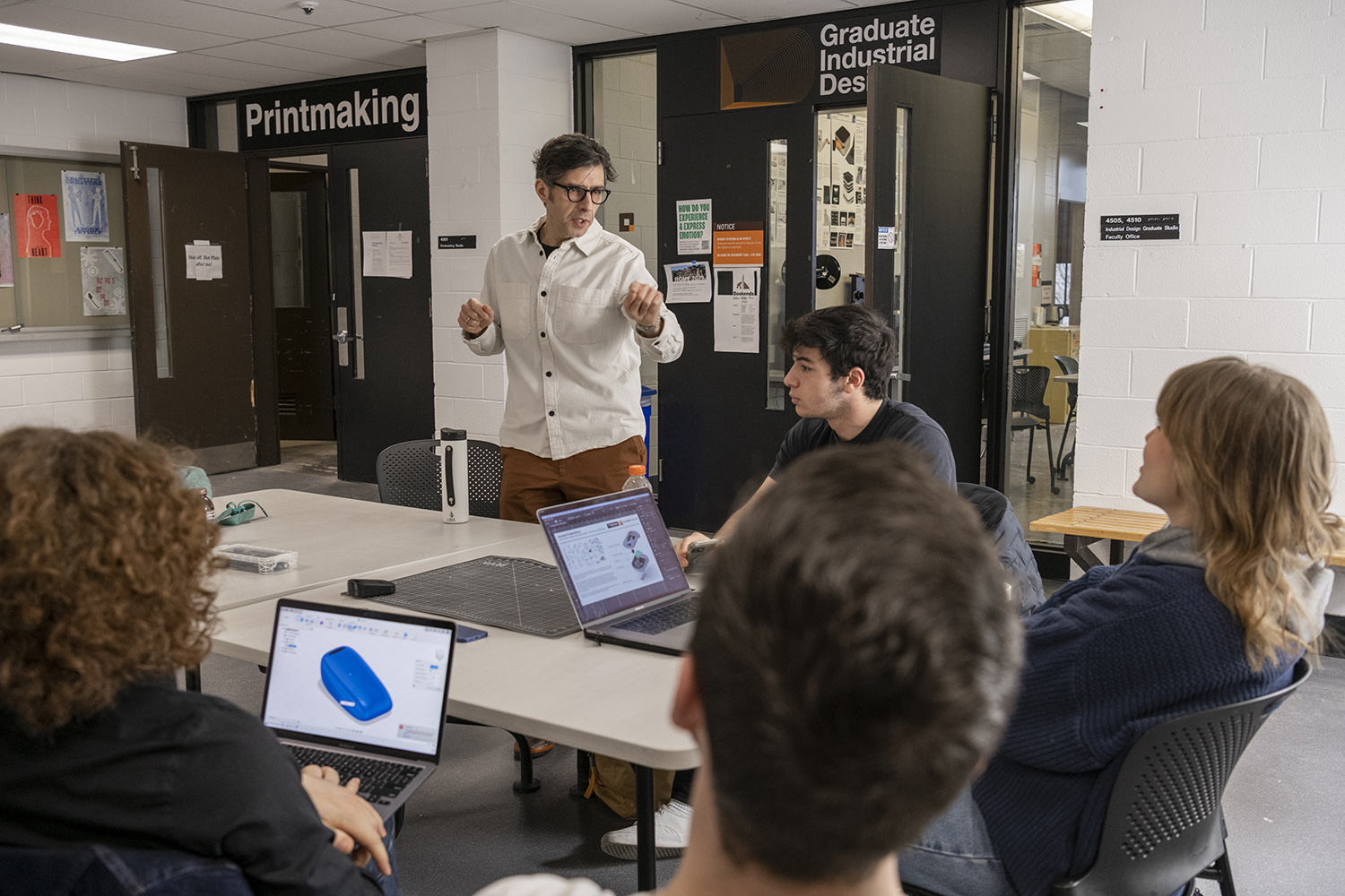 Alex Lobos talks with students sitting at a table.