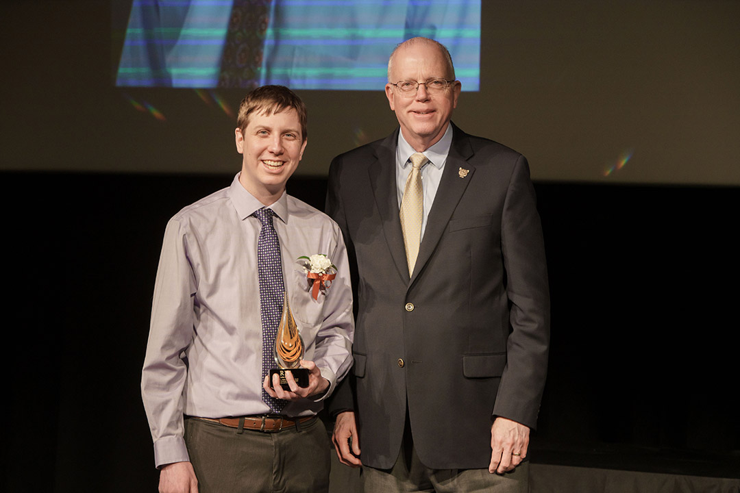 award winner and President Munson posing on stage.