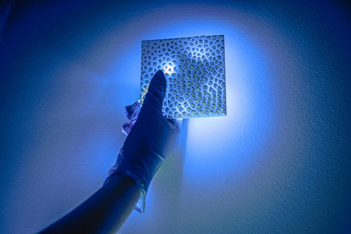 A 3D-printed nylon piece held under a blue light.