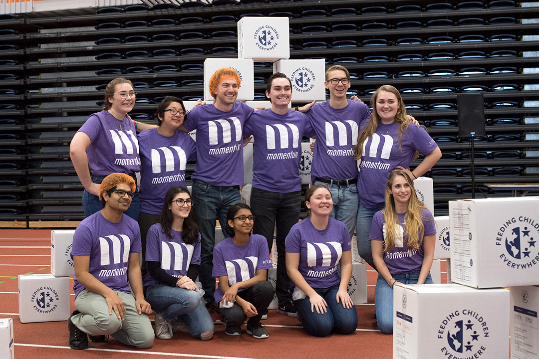 group of 11 students posing wearing purple T-shirts.