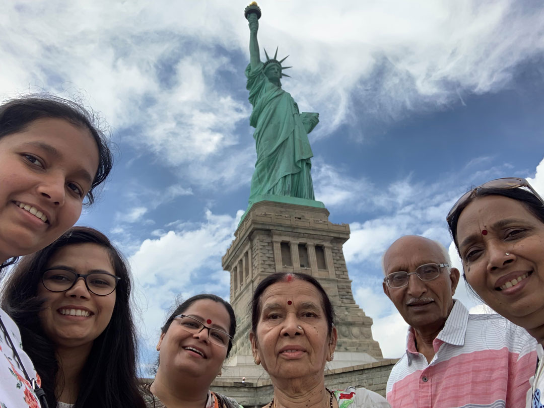 A group of people pose for a photo in front of the Statue of Liberty.