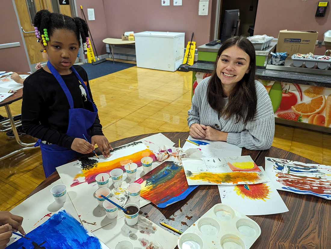 An RIT artist teacher paints with a young student.