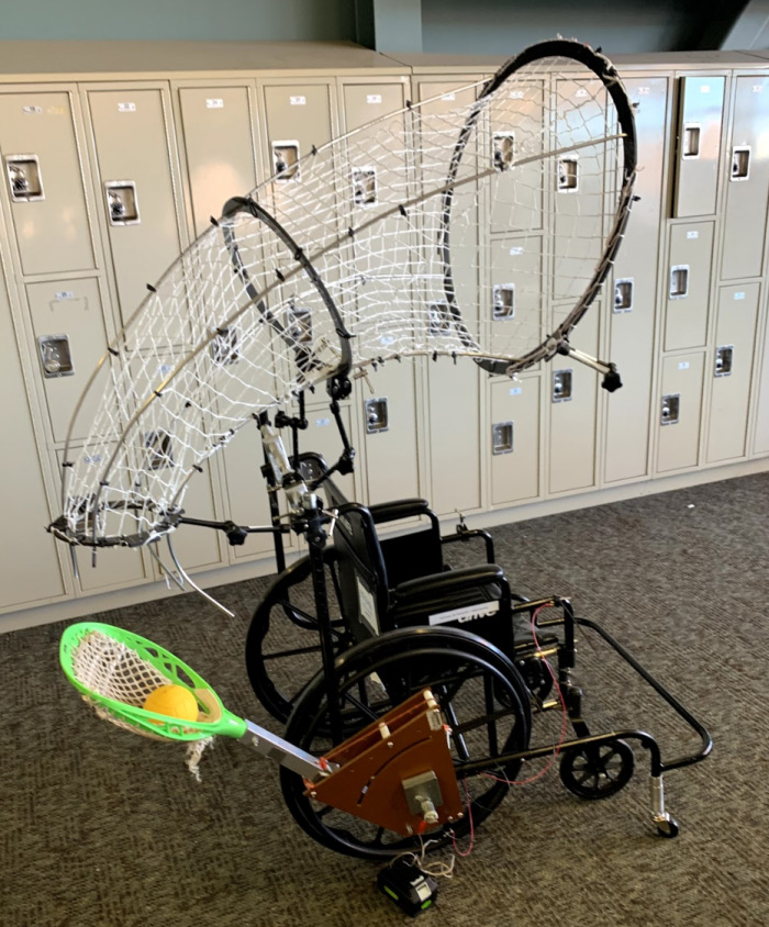 Wheelchair outfitted with a net to catch a ball and the pocket from a lacrosse stick to throw the ball.