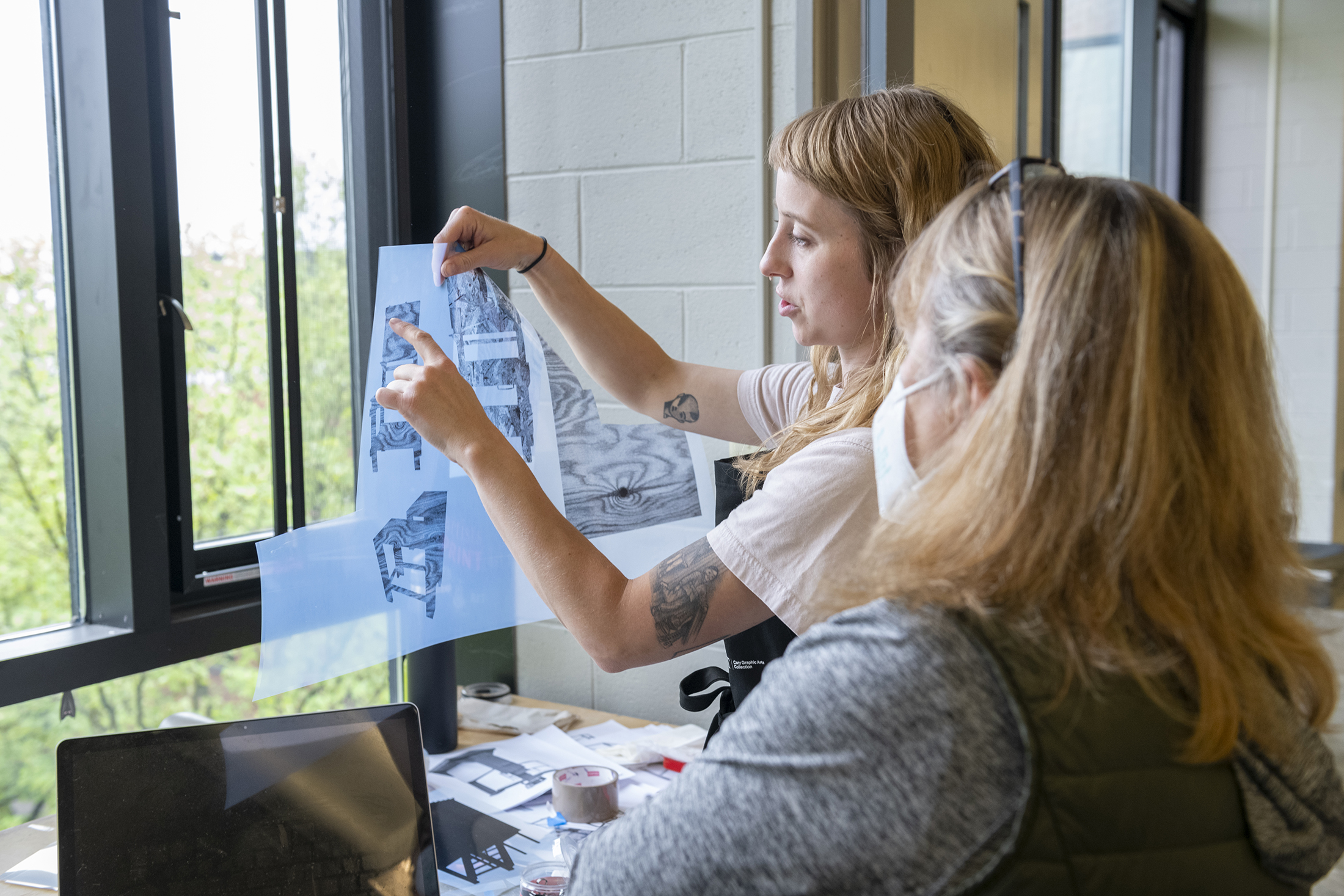 Heather Swenson shows off her printmaking work to studio visitors.