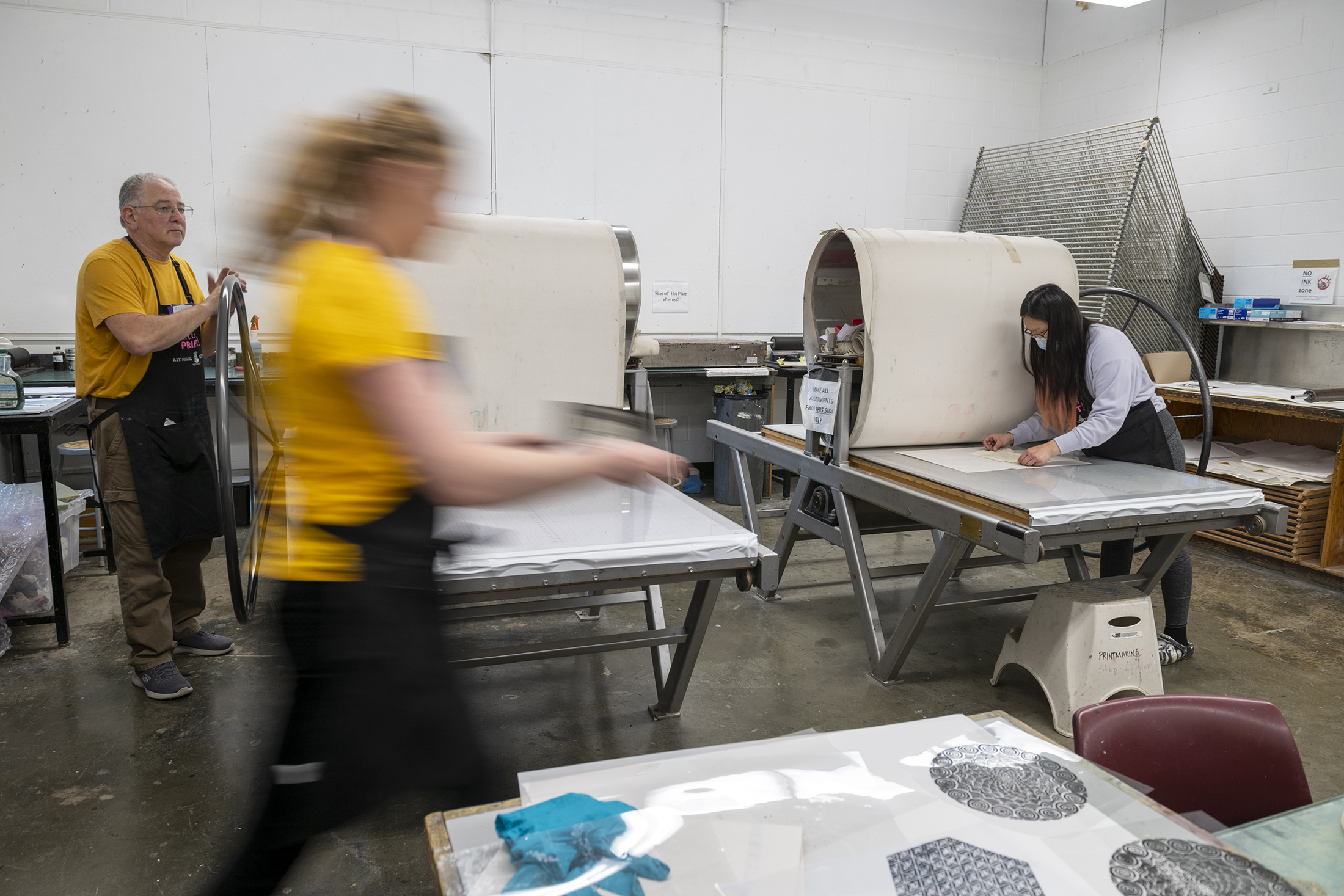 A blurred photo showing RIT's printmaking studio in action.