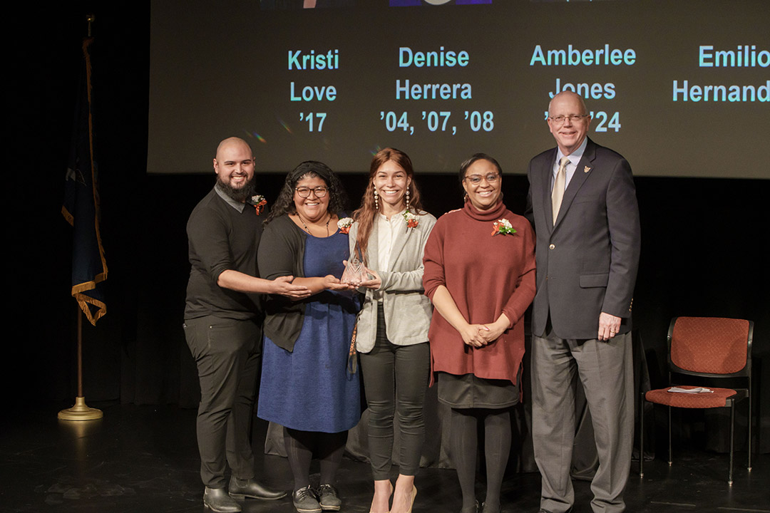 four award winners and President Munson posing on stage.