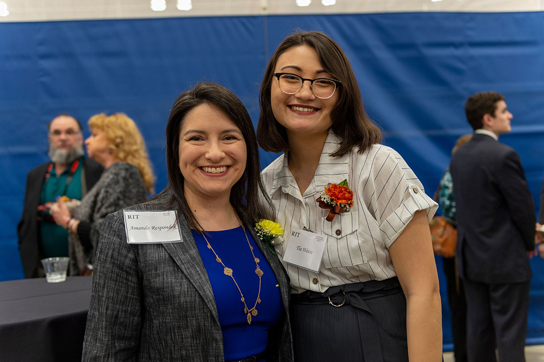 Teacher and student stand next to each other at award ceremony.