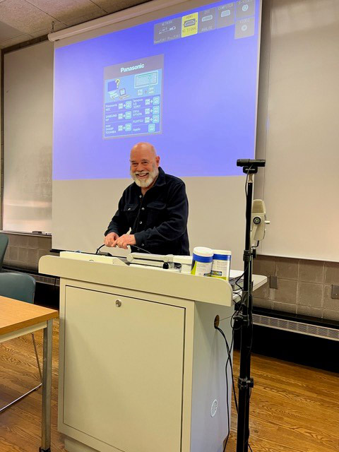 professor standing at a podium in a classroom.