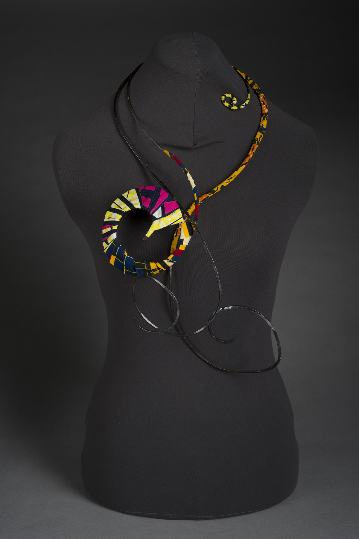 A colorful jewelry piece is displayed on a mannequin.