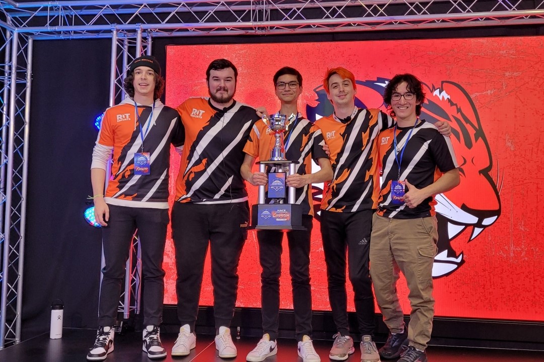 Student stand on a stage with the center person holding a trophy