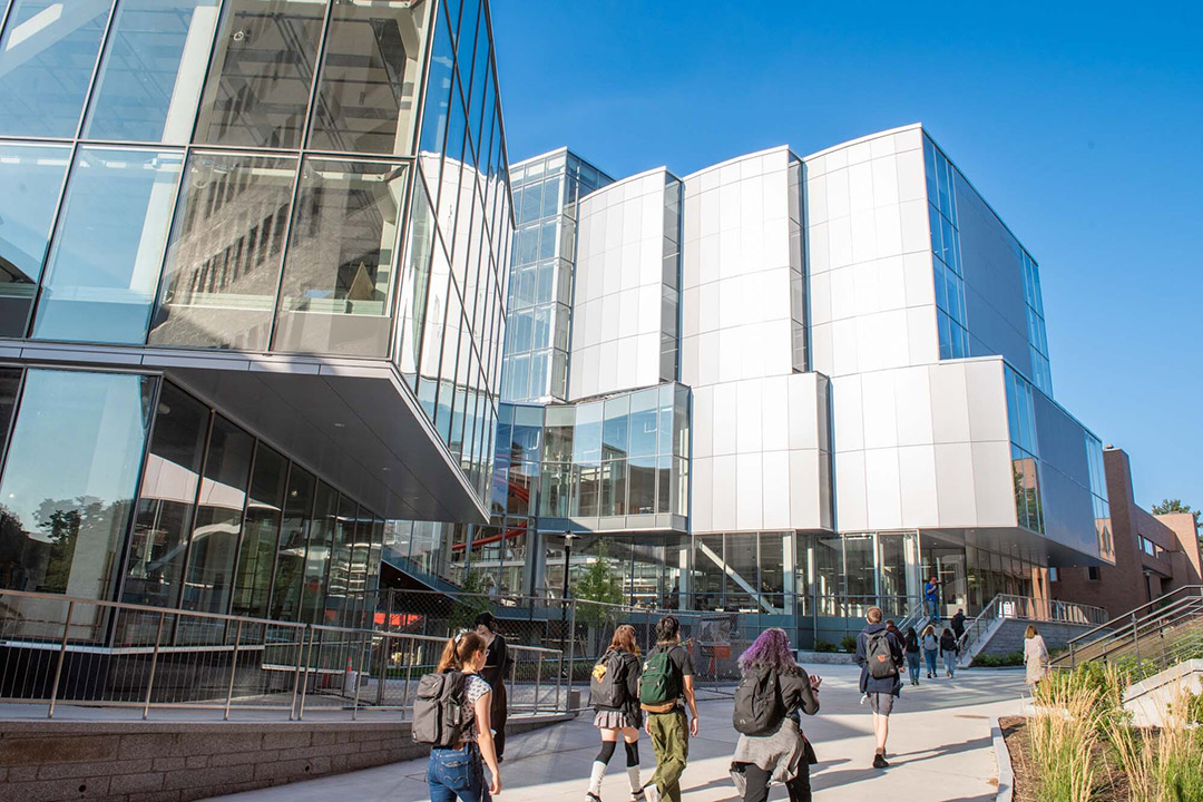 college students walking to class in a large glass building.