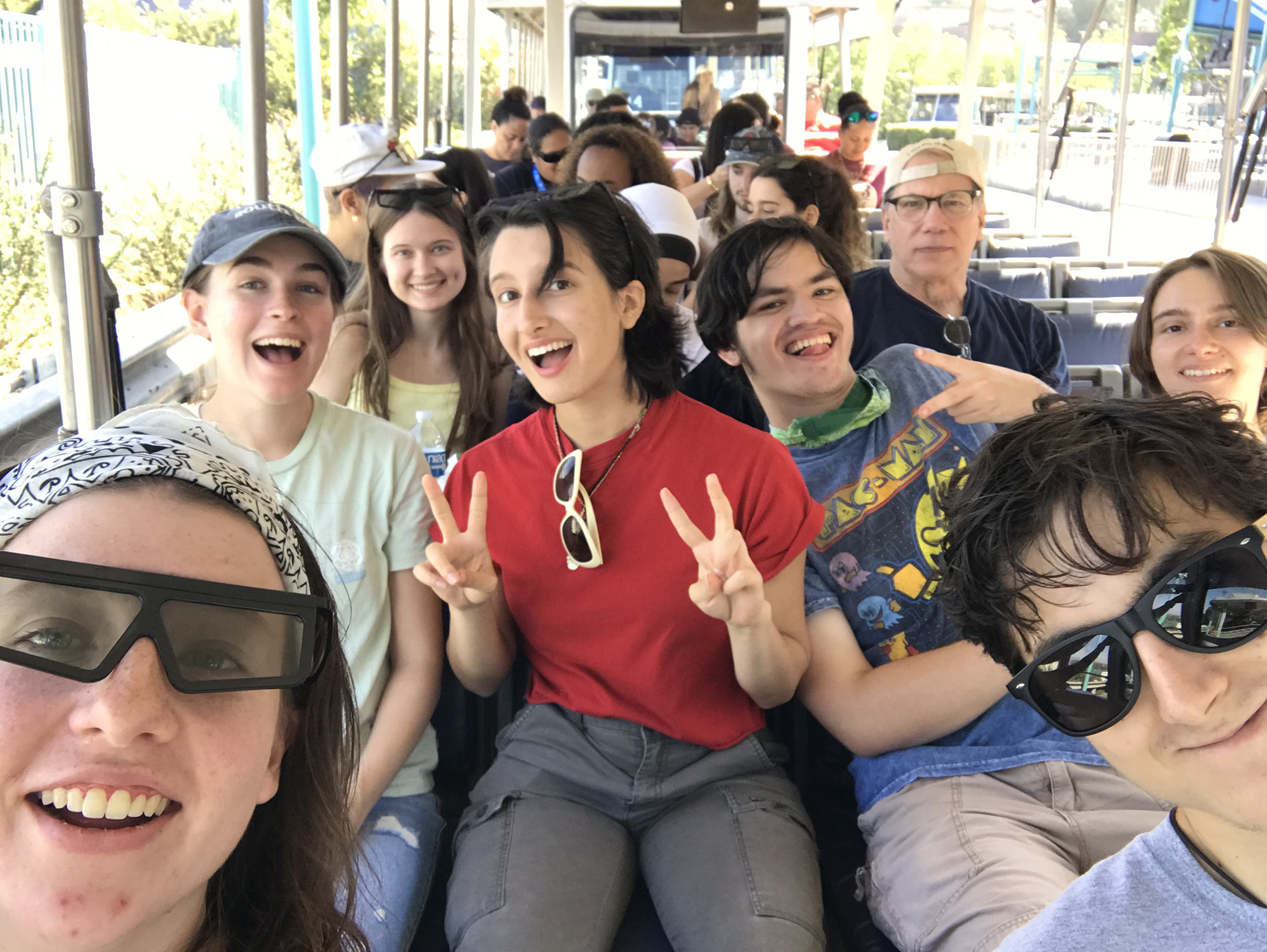 A group of student take a group selfie on a bus.