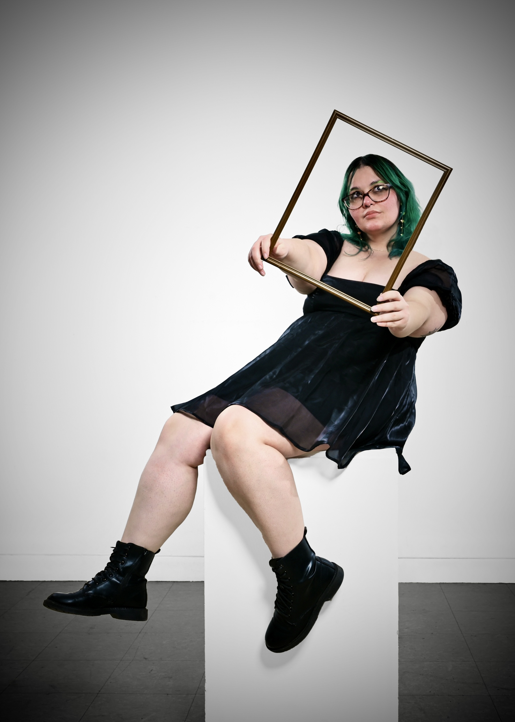 Skylier Grooms holds a picture frame in front of her, set against a white background.