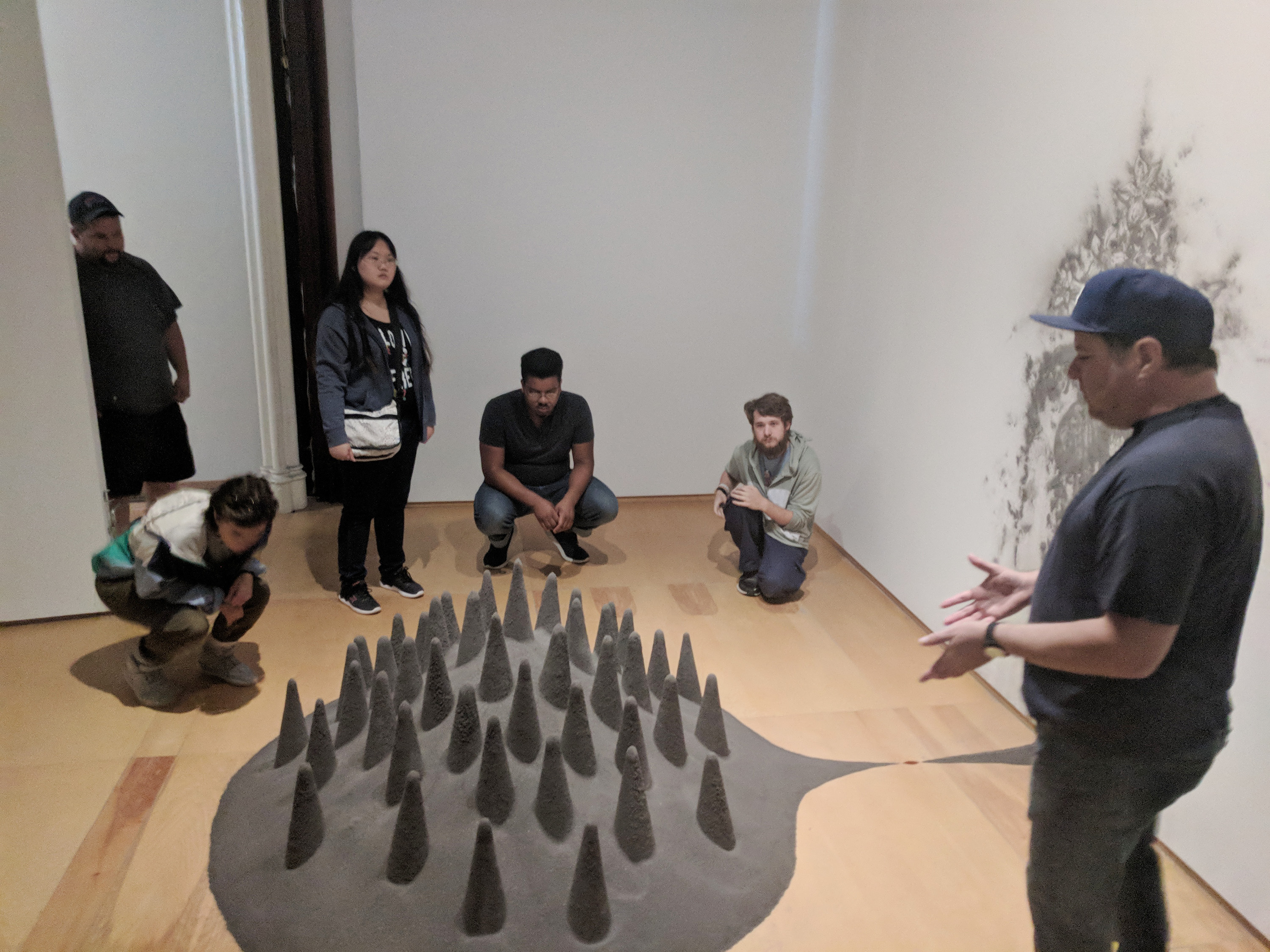 Students kneel to get a closer look at an art installation.