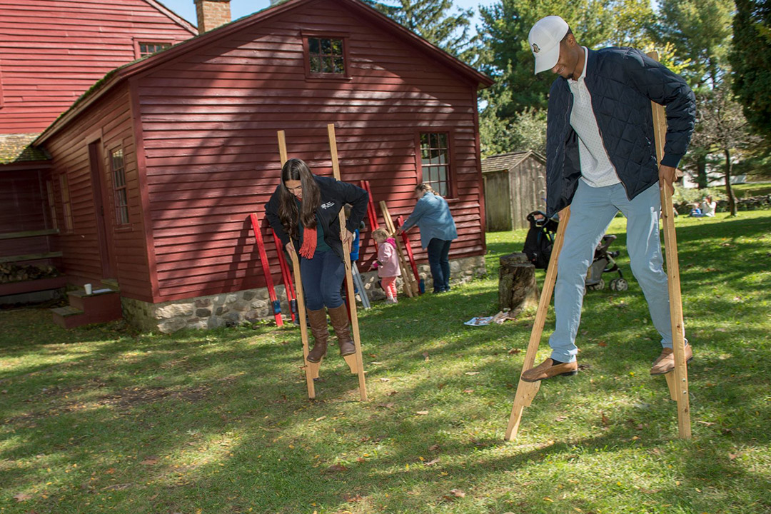 two students walking outdoors on stilts.