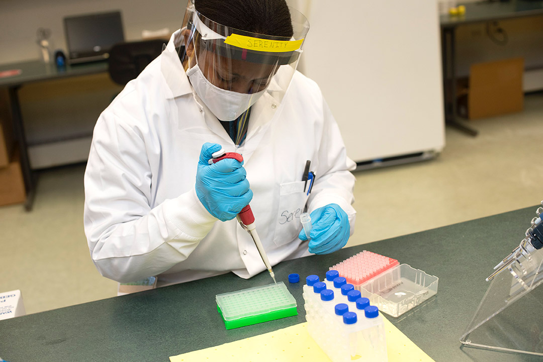 student wearing PPE using a pippette.