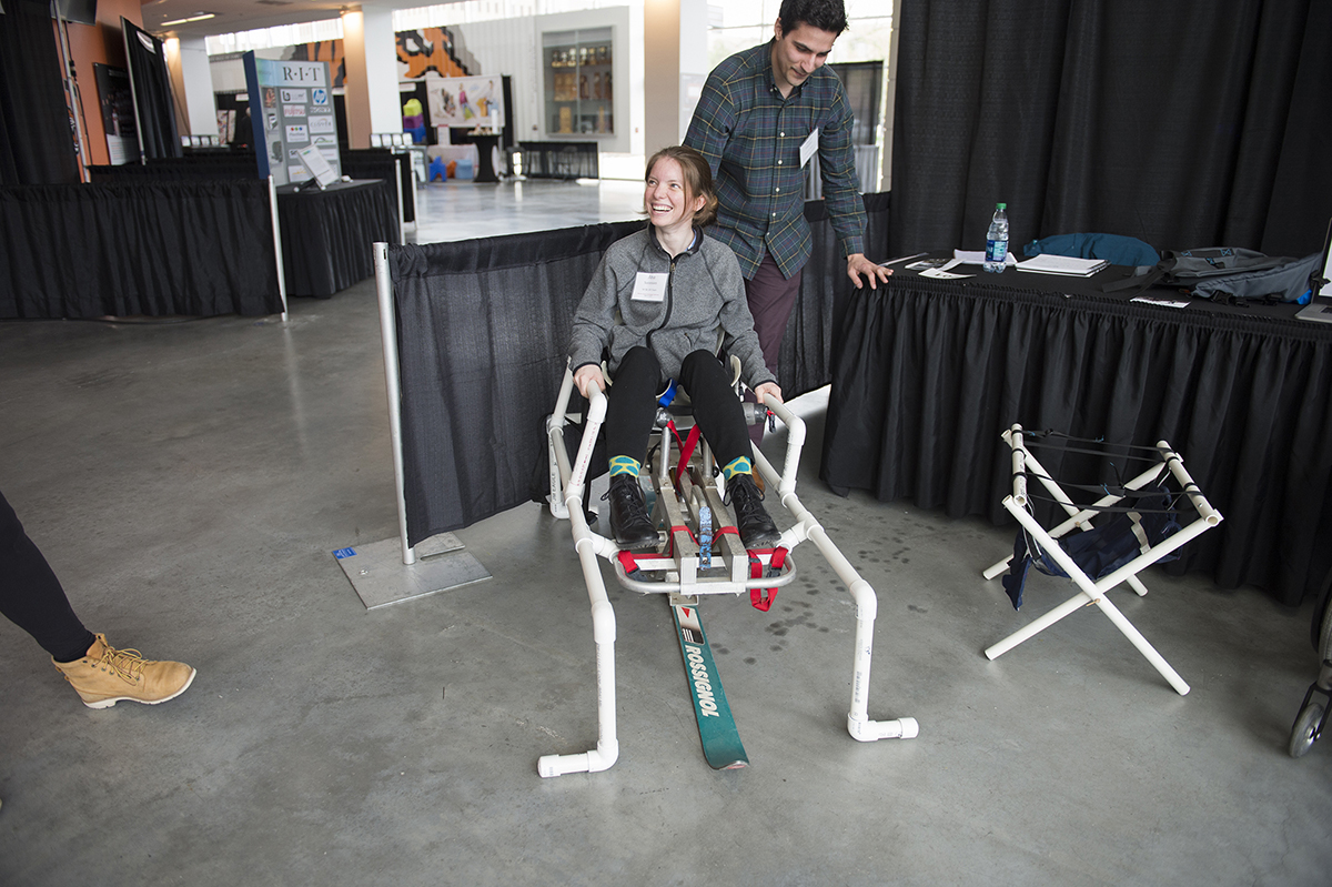 A student creator demonstrates the transfer ski lift design at a conference.