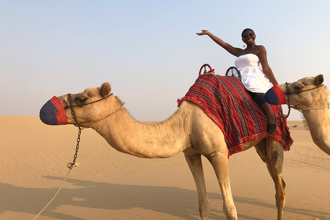 woman riding camel in desert.