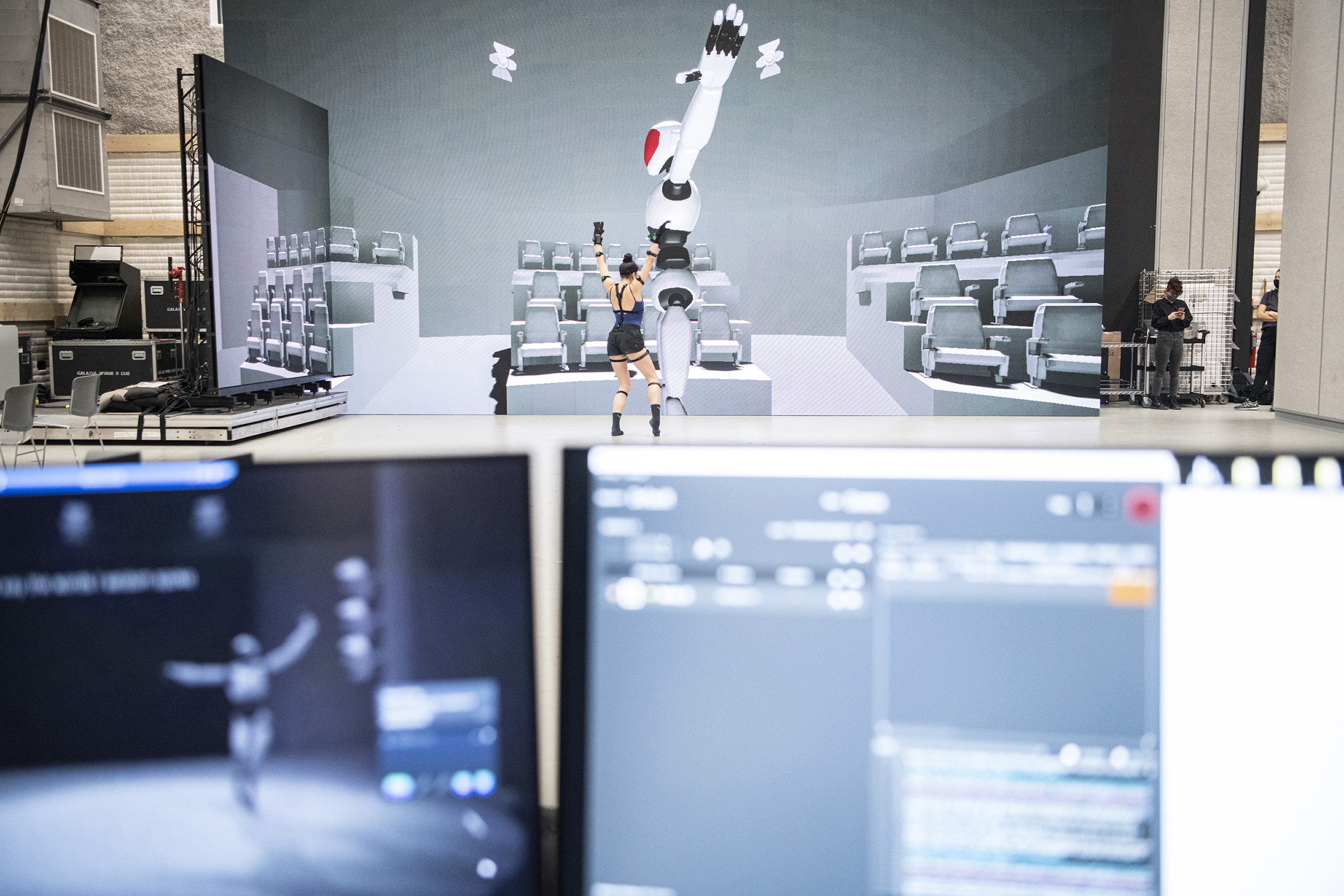 A motion capture actor stands in front of a large LED screen.