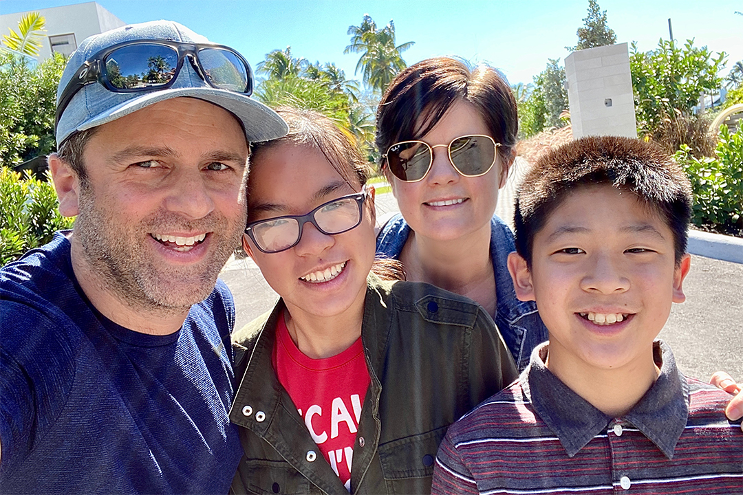 Four people outside in a sunny day smiling at the camera.