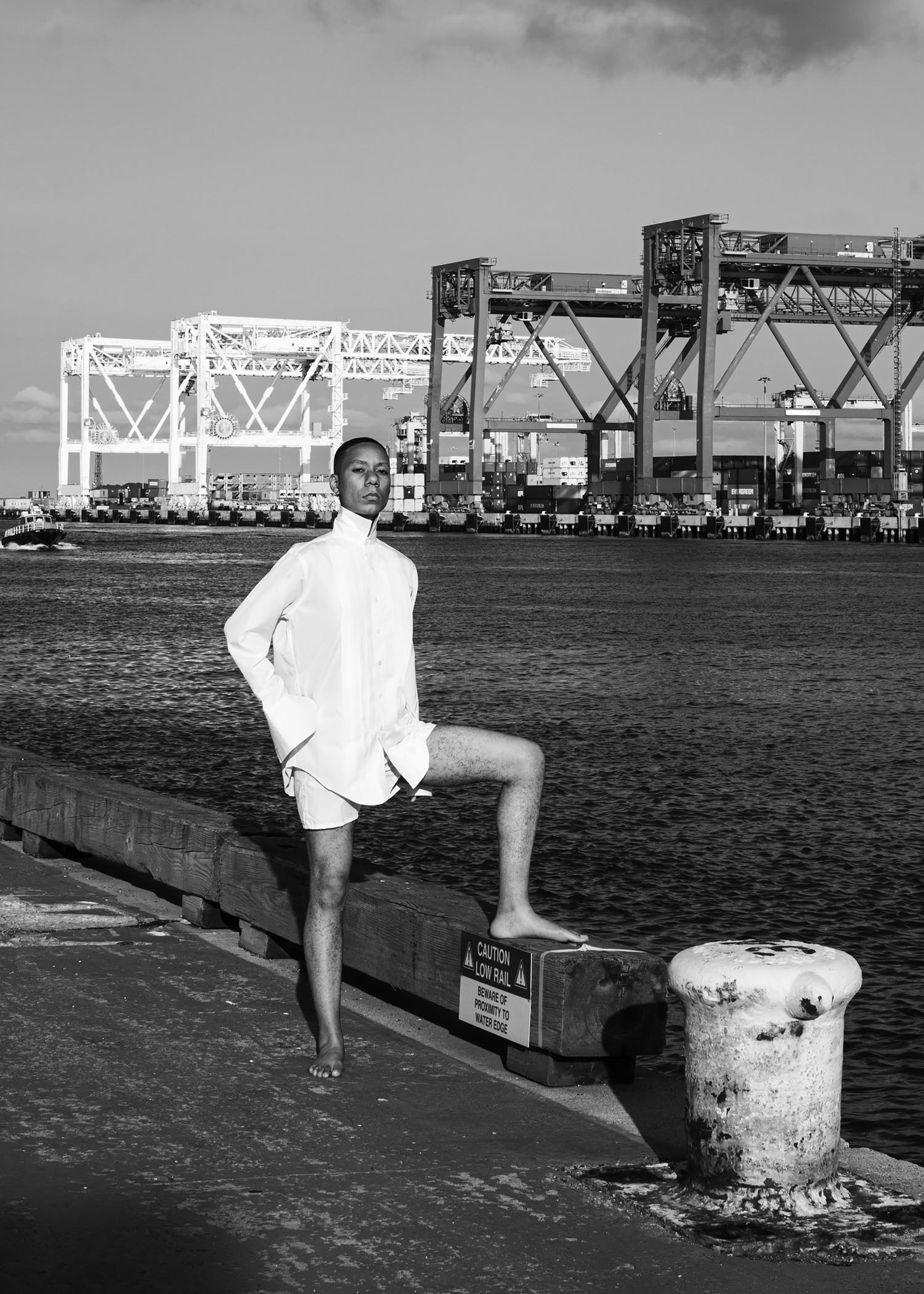 A self-portrait of CR Smith along a waterfront, wearing a white dress shirt.