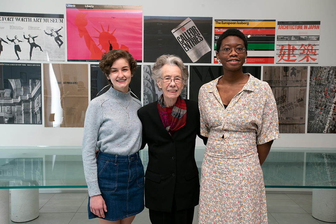 two students standing on either side of retired dean.