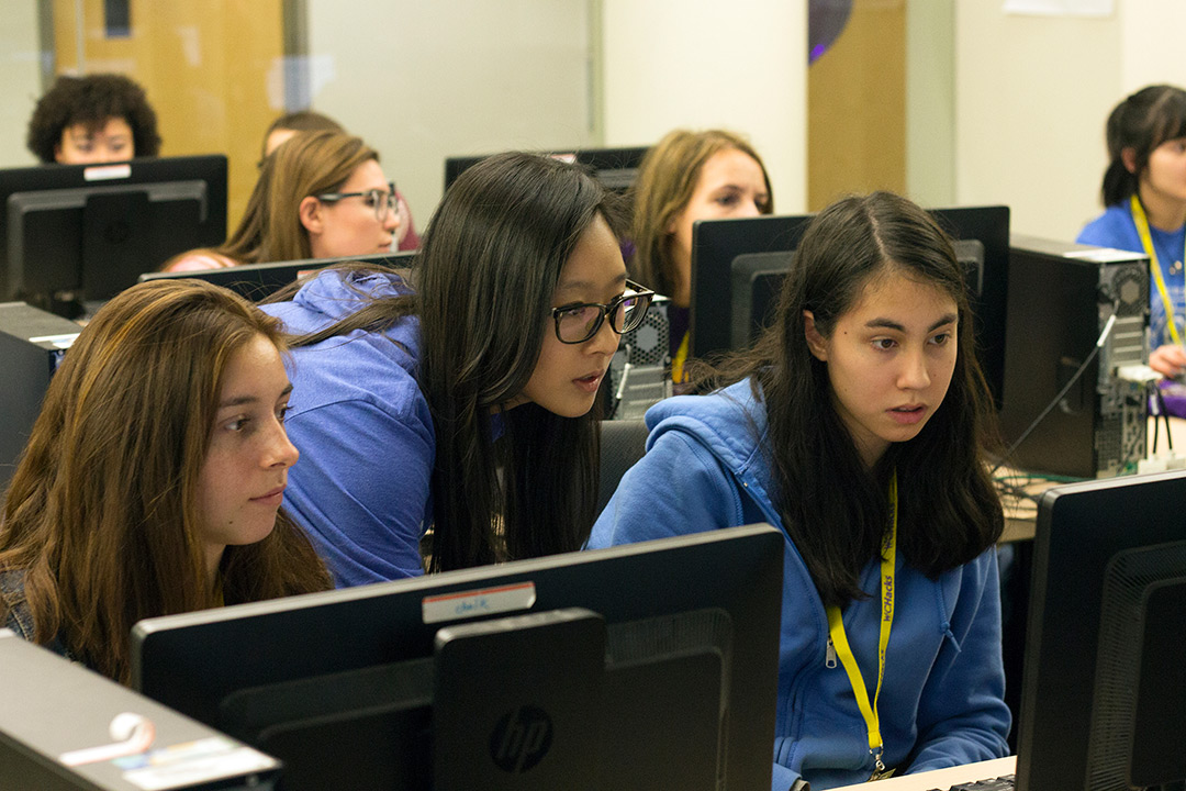 A group of young women focusing on their computer screens during the hackathon.