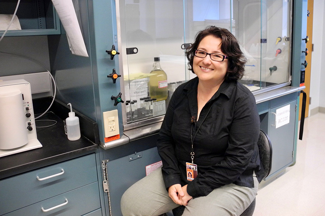 Patricia Taboada-Serrano poses for a photo in front of a fume hood in a lab.