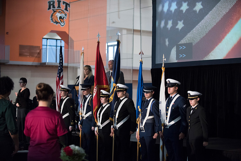 Members of the ROTC stand in a line and hold flags to honor those who have served.