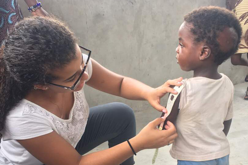 Woman measures arm of child with strip to determine anemia.