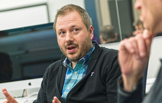 A headshot of Matt Huenerfauth talking to a colleague.