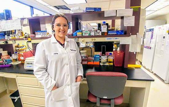 Portrait of Ashley Adair in a lab wearing a white coat and glasses.