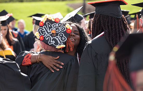 two graduates hugging. graduate cap saying "class of 2018".