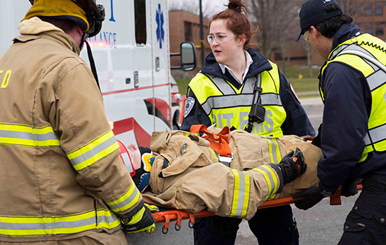 Three people in uniform putting a person on a gurney in the ambulance.