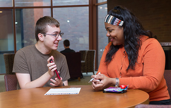 student and staff member talking at a table.