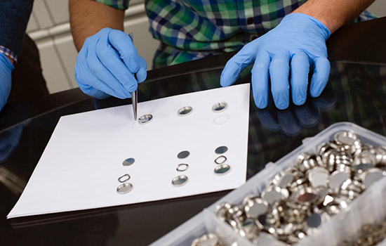 A person in gloves working with batteries.