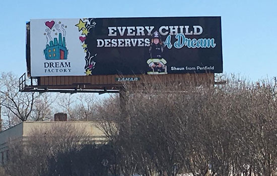 A photo of the billboard designed by the advertising and promotion management class. It reads, "Every Child Deserves A Dream" in large text on the right, and on the left there is a illustrated photo of a small factory with the words "Dream Factory" written below.